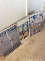 Three framed Bully Hill Vineyards prints leaning against a wall showing all three with visible frames and art themes.