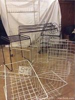 Overview photo showing multiple wire metal racks and baskets including white and black wire items, positioned for sale display.