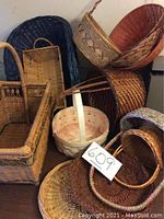 Several woven baskets of various styles, shapes, and colors arranged together, with a lot number tag visible.