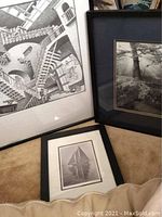 Three framed black and white art prints shown together. One large surreal staircase print, one forest landscape print, and one smaller sailboat print.