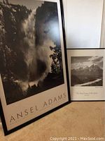Two framed black and white Ansel Adams prints leaning against a wall, view showing both pieces including titles and framing.