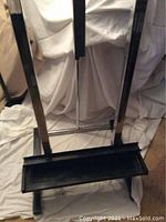 Front view of the metal easel showing the vertical bars and attached tray shelf.
