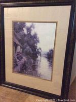 Full view of framed print showing the entire 'Cabin By the River' artwork with dark wood frame and triple matting.