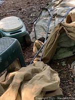 View of both gardening stools and several outdoor furniture covers with shepherd hooks placed on covers, on mulch ground.