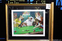 Framed color lithograph showing five dogs playing pool in a gold frame with glass pane and black mat, ruler included for scale.