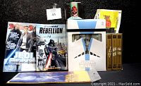 Photo showing multiple Star Wars collectibles including magazines, books, trading cards, DVDs, and the boxed vinyl figure.