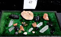 Full view of assorted healing stones and crystals on green velvet display inside a box
