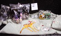 Lot display on grey cloth with Disney collectibles including packaged McDonald's toys, Welch's Jelly Bottles, and a celery green Bambi top