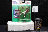 Photo showing the 1996 Jerry Rice action figure in sealed packaging, with trading card visible, accompanied by the Pinnacle 97 football cards can placed on a white box.