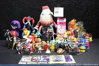 Wide shot showing about 40 assorted toys including plush, PVC figures, Happy Meal toys, and animal and cartoon characters arranged on a black surface.