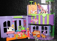 Polly Pocket playset showing two-story cafe salon with a doll and animal figures on various levels with colorful plastic furniture and accessories.