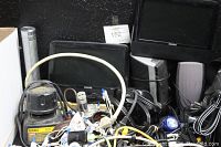 Box containing various electronic accessories including cables, a Philips digital photo frame, small speakers, and a DeWalt flashlight.