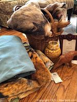 Full lot arranged showing fleece blankets, basket, wood figurines, ceramic vase, and framed artwork