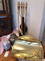 Photo showing two decorative vases: a ceramic floral vase and a lidded urn-style vase with detailed patterns, along with a brass fireplace basket and a set of fireplace tools on a stand
