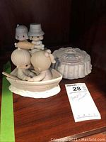 Kissing couple in a boat, and behind it a Pilgrim couple figurine on a wooden shelf