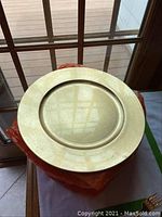 Gold colored round charger plate measuring 13 inches diameter, showing front view with slightly textured gold surface.