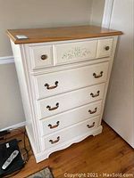 Full view of white dresser with wood top and 5 drawers on hardwood floor.