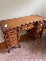 Front view of vintage wood desk showing seven drawers and overall condition.