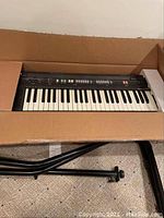 Overall view of Casio CT-360 keyboard in original packaging with keyboard stand parts in the box.