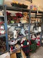 Full view of six shelves filled with various holiday decor items including ceramic serveware, plush figurines, wreaths, and other Christmas decorations.