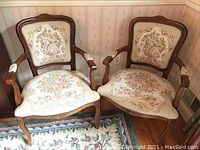Pair of two tapestry accent chairs made in Italy shown side by side on floral carpet in room with wallpaper.