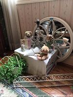 Photo showing entire lot including large round decorative mirror, two wire shallow shelves, lamp base, faux plant, and small decorative items arranged on box.