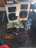 Two off-white ADS SAT6 satellite speakers with cables and media on floor