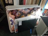 Stack of unframed photos in plastic sleeves showing an architectural photo with clock faces and several smaller photos underneath.