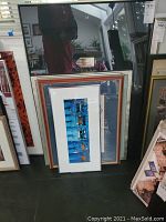 Six framed wall art prints stacked against a wall showing denim-themed photographic prints.