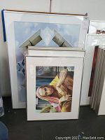 Photo showing a set of framed photographic prints, with one portrait of an elderly person in colorful shawl in front.