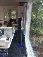 Front view of entire floor lamp next to window and table.