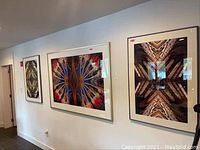 Three framed prints hung on a white wall: one large horizontal and two smaller vertical prints.