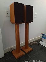 Both speakers mounted on stands against wall