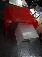 Red glass side table and frosted acrylic stand on tile floor shot from above