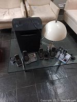 Overview photo showing all lot items on a glass table including shredder, lamp, and multiple Uniden phones and answering systems.