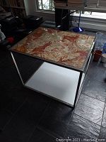 Full view of the side table showing chrome frame, stone top, and lower shelf