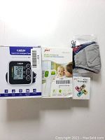 Photo showing CAZON blood pressure monitor box, JZIKI thermometer box, JZIKI pulse oximeter box, and a stack of reusable masks.