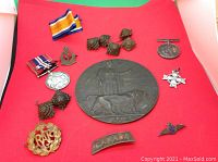 Full lot on red background showing bronze plaque, medals with ribbons, badges and shoulder titles