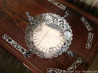 Top-down view of entire silver card holder showing ornate openwork gallery, scalloped rim and four feet