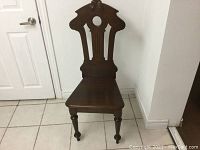 Front view of the solid walnut Victorian hall chair showing carved backrest and flat seat