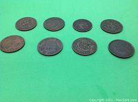 Eight copper coins and tokens laid out on green background