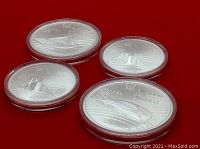 Group of four silver coins in acrylic capsules on red background