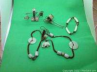 Overview of all items including two silver miniatures, silver bracelet, and jade necklace with pendants on red cord.