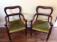 Front view of both chairs showing curved open backs, arms, and green upholstered seats