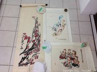 Three scrolls laid flat on tile floor, showing front images and overall display