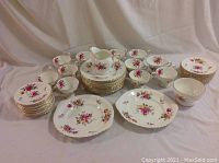Overview of 12 cups, saucers, luncheon and bread plates, two platters, cream pitcher and sugar bowl arranged on backdrop