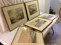 Five framed hunting prints arranged on table