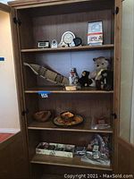Cabinet contents showing shelves filled with clocks, stuffed animals, decorative baskets, books, postcards and other items