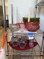 Shelf with colorful vintage carnival glass bowls, clear crystal and glass vases, and bowls arranged together, showing variety of sizes and shapes