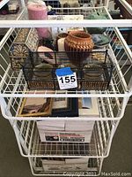 Photo showing various home decor items including candles, small containers, picture frames, and hangers on a metal rack.